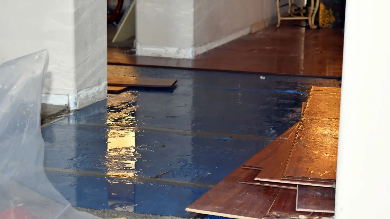 Hardwood boards and plastic sheeting on a floor being repaired after water damage